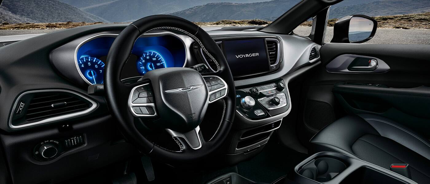 The steering wheel, Digital Cluster Display, Uconnect touchscreen and center stack controls in a 2026 Chrysler Voyager LX.