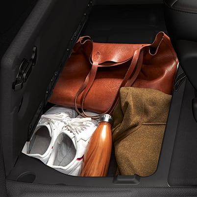 Second-row floor storage bin holding travel items in a 2026 Chrysler Voyager.