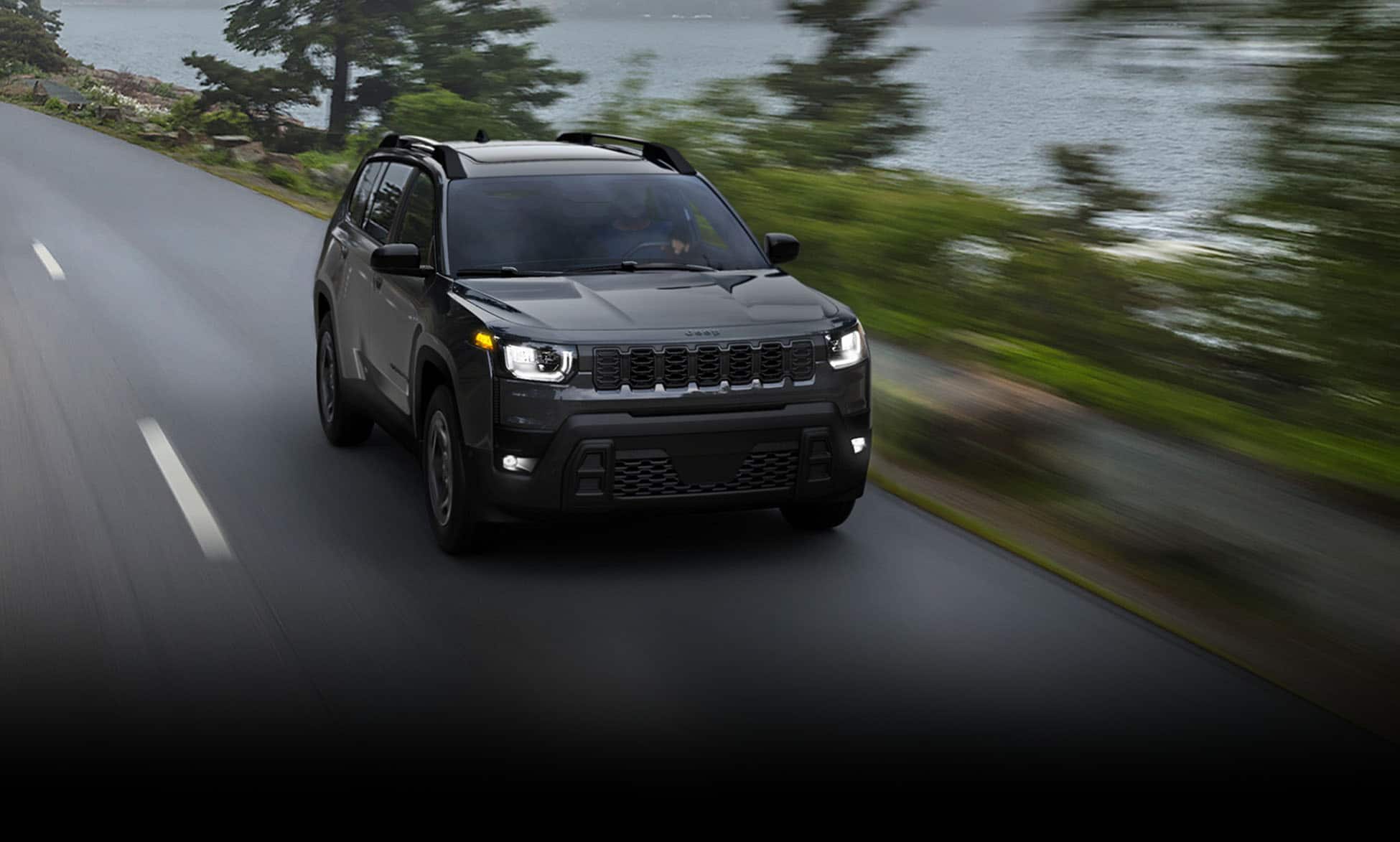 Dark 2026 Jeep Cherokee driving on a wooded road.
