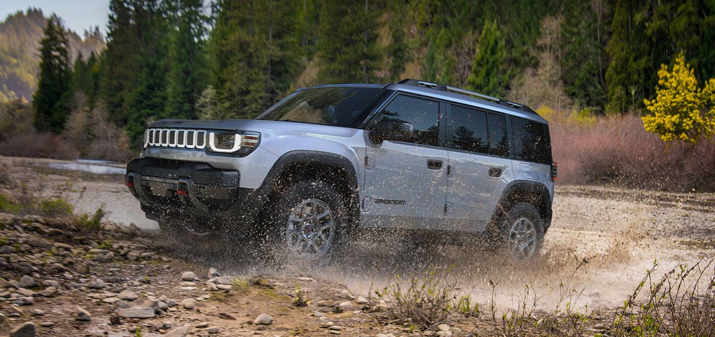 A silver 2026 Jeep Recon Moab exiting a muddy stream off-road.