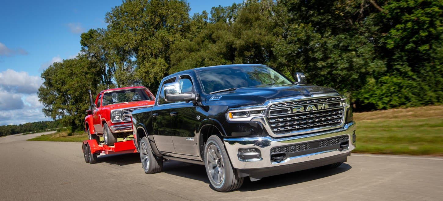 A black 2026 Ram 1500 Limited Longhorn 4x4 Crew Cab towing a red pickup.