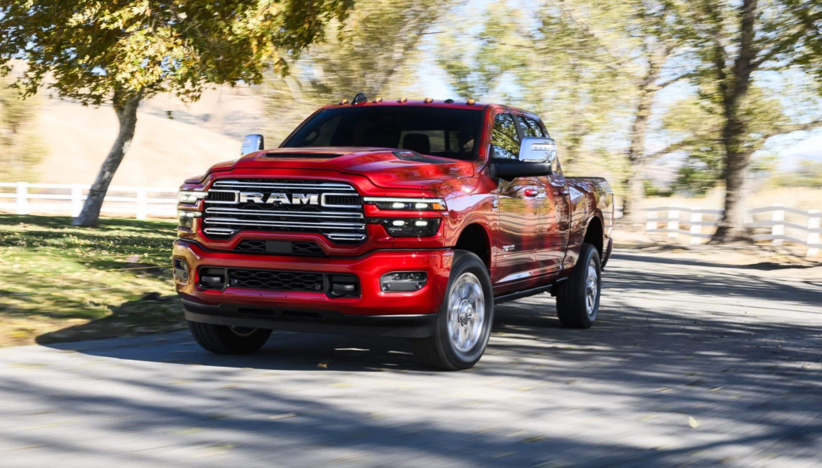 A Red 2026 Ram 2500 Laramie heavy duty truck traveling down a paved country road.