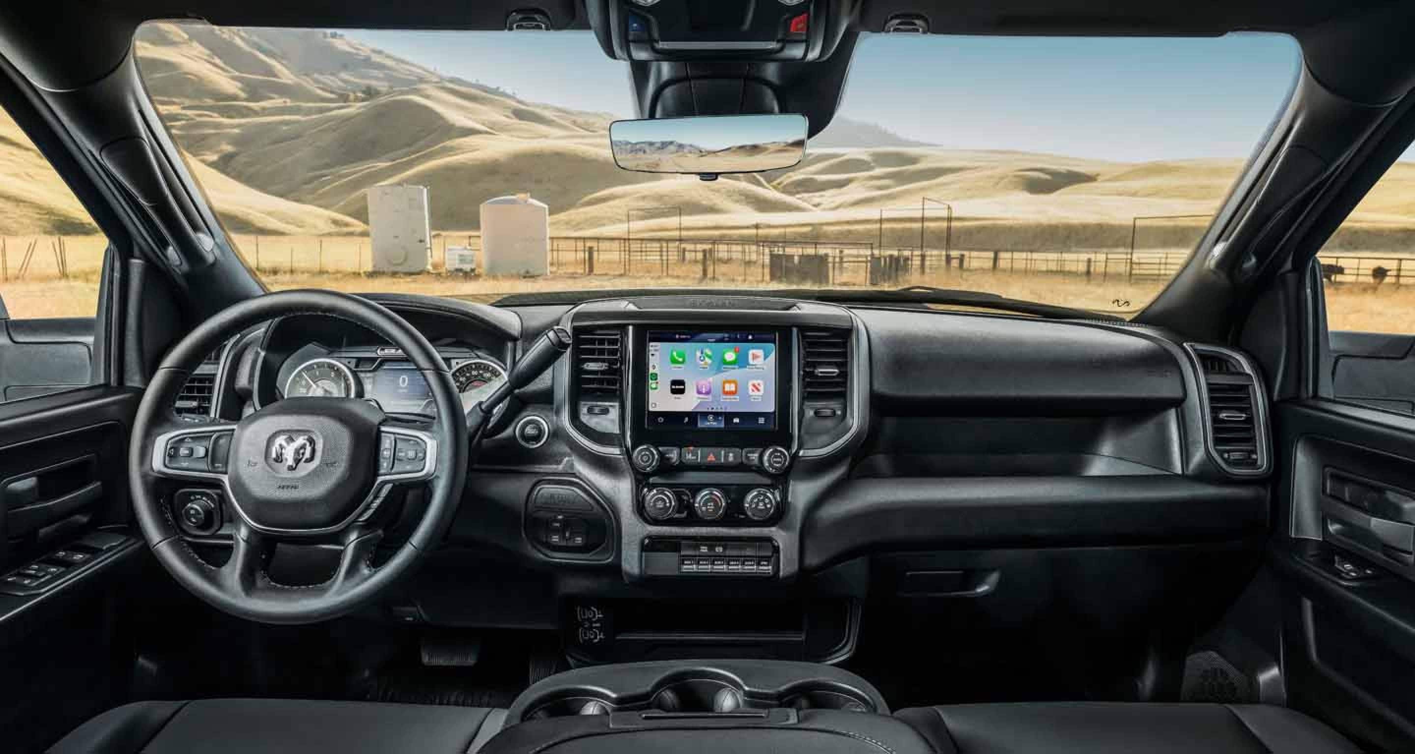 The front seat area of a 2026 Ram Tradesman Chassis Cab focusing on the steering wheel, Digital Cluster Display, Uconnect touchscreen and center stack controls.