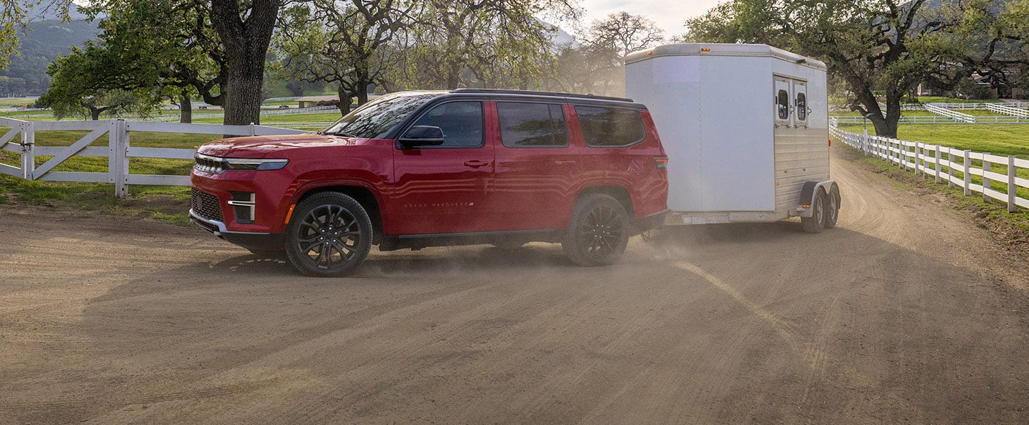 Red 2027 Jeep Grand Wagoneer towing a trailer