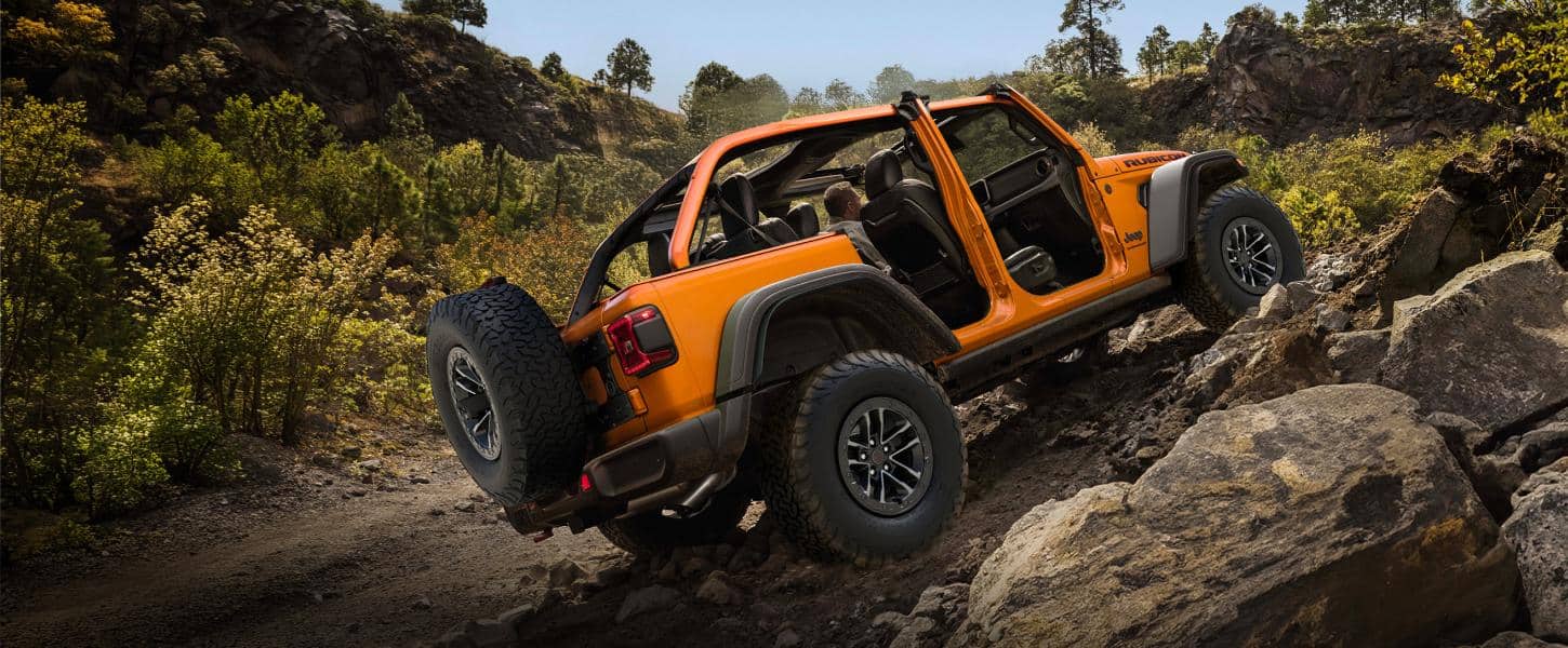 Orange 2027 Jeep Wrangler with doors removed climbing rocky terrain