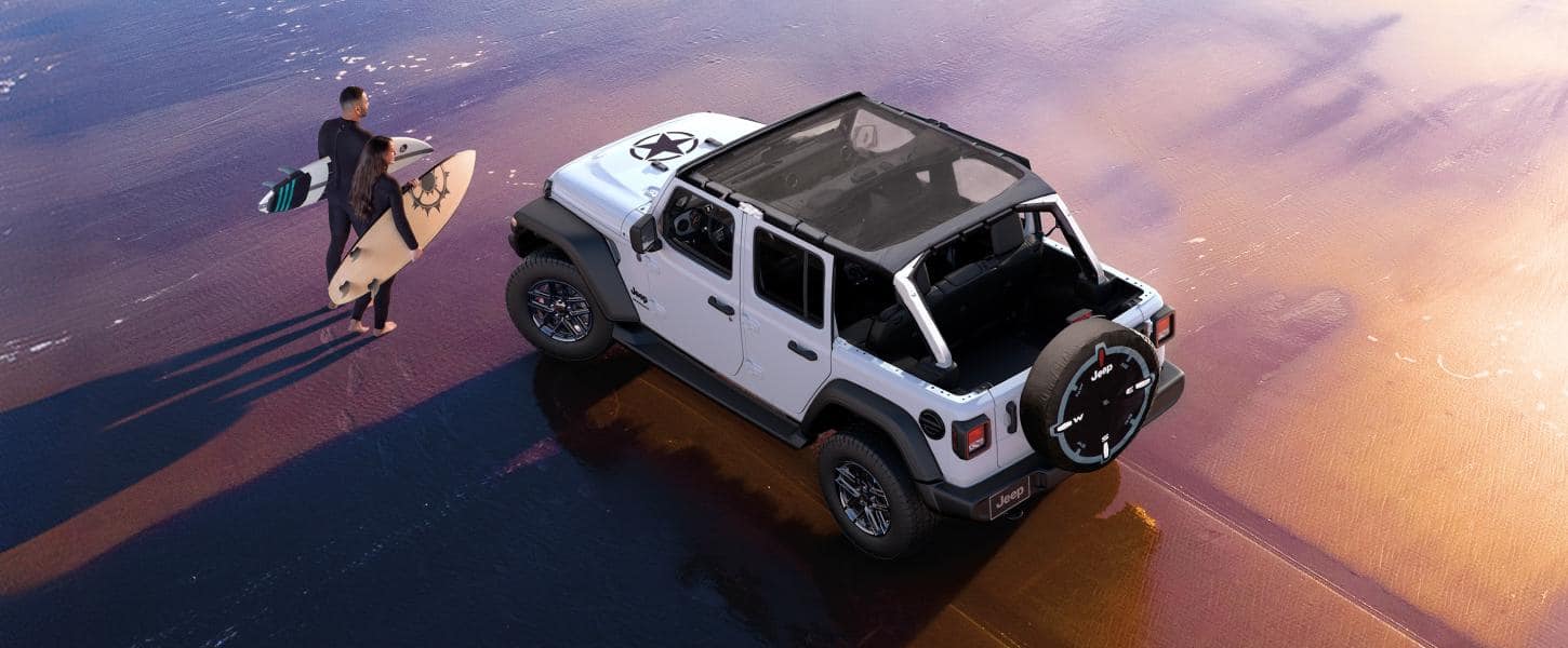 White 2027 Jeep Wrangler with open roof beside a surfer on a beach