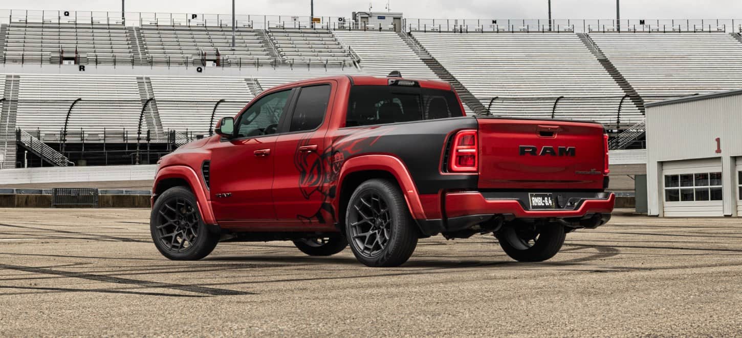 A rear angle of a red 2027 Ram 1500 Rumble Bee 392 Track Pack 4x4 Quad Cab with special bedside splash graphics.