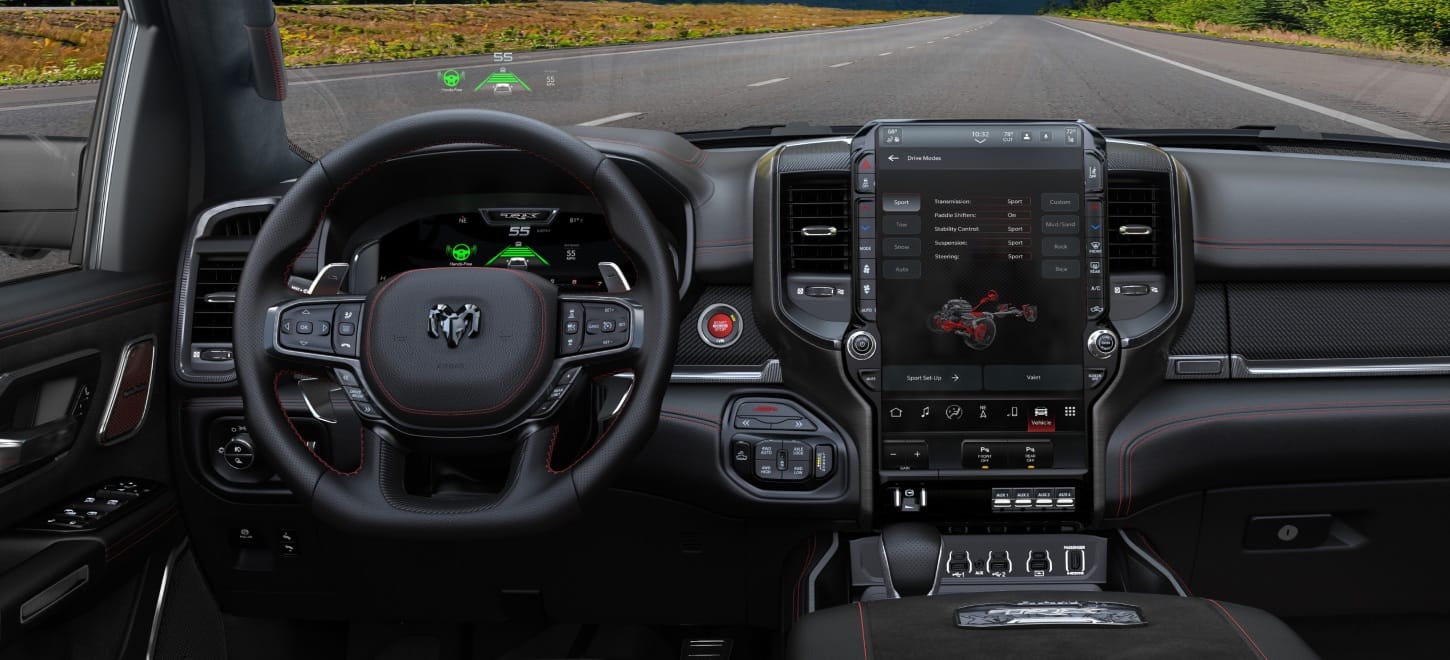 The interior of a 2027 Ram 1500 TRX SRT, focusing on the steering wheel, Digital Cluster, Head-Up Display, Uconnect touchscreen and center stack controls.