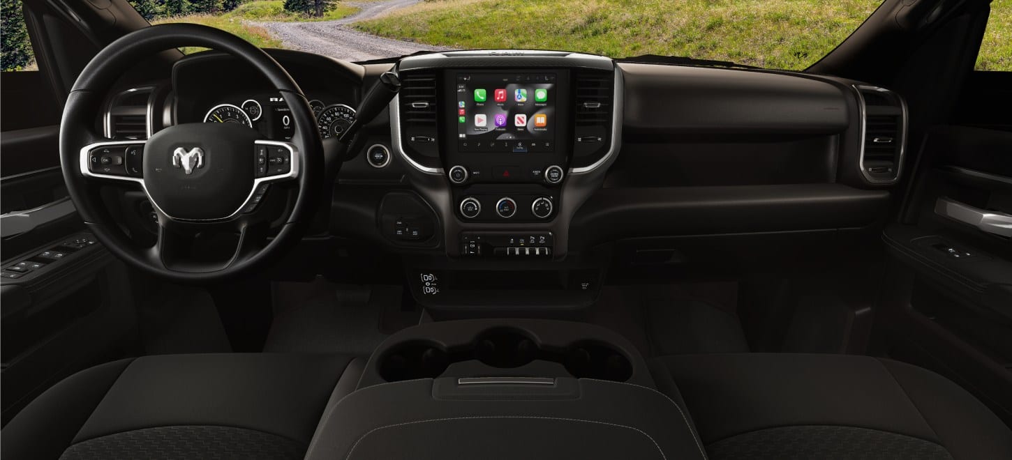 The steering wheel, Digital Cluster, Uconnect touchscreen, center stack controls and center console in a 2027 Ram 2500 Heavy Duty Tradesman pickup truck.