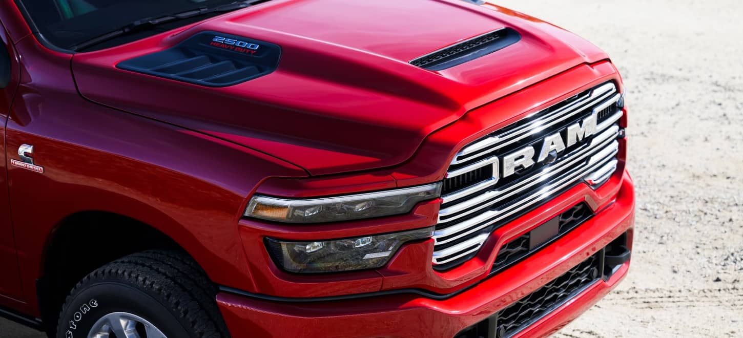 The Mopar Sport Performance hood with unique 2500 Heavy Duty hard badging on a red 2027 Ram 2500 Heavy Duty Laramie pickup truck.